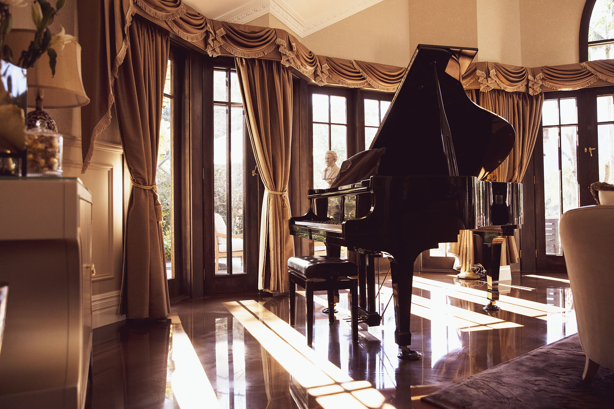 Hermitage Estate living room with baby grand piano and spectacular views out over the terrace, lush gardens and escarpment