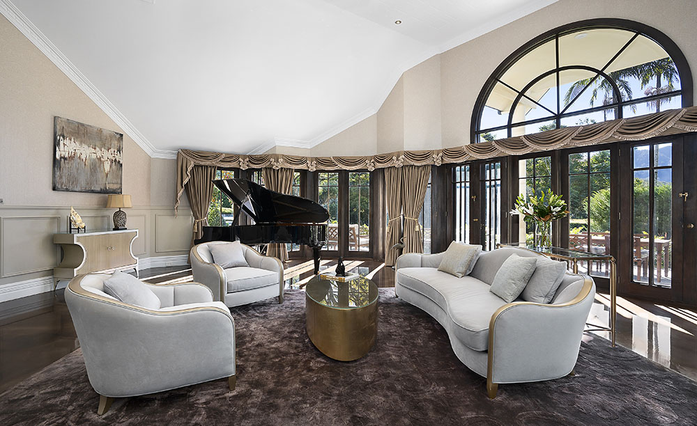 Hermitage Estate living room with baby grand piano and spectacular views out over the terrace, lush gardens and escarpment